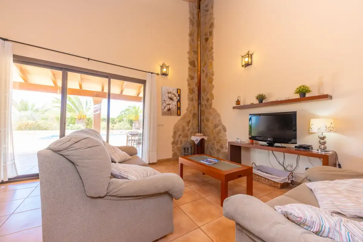A living room with seating, a television, and a stone fireplace.