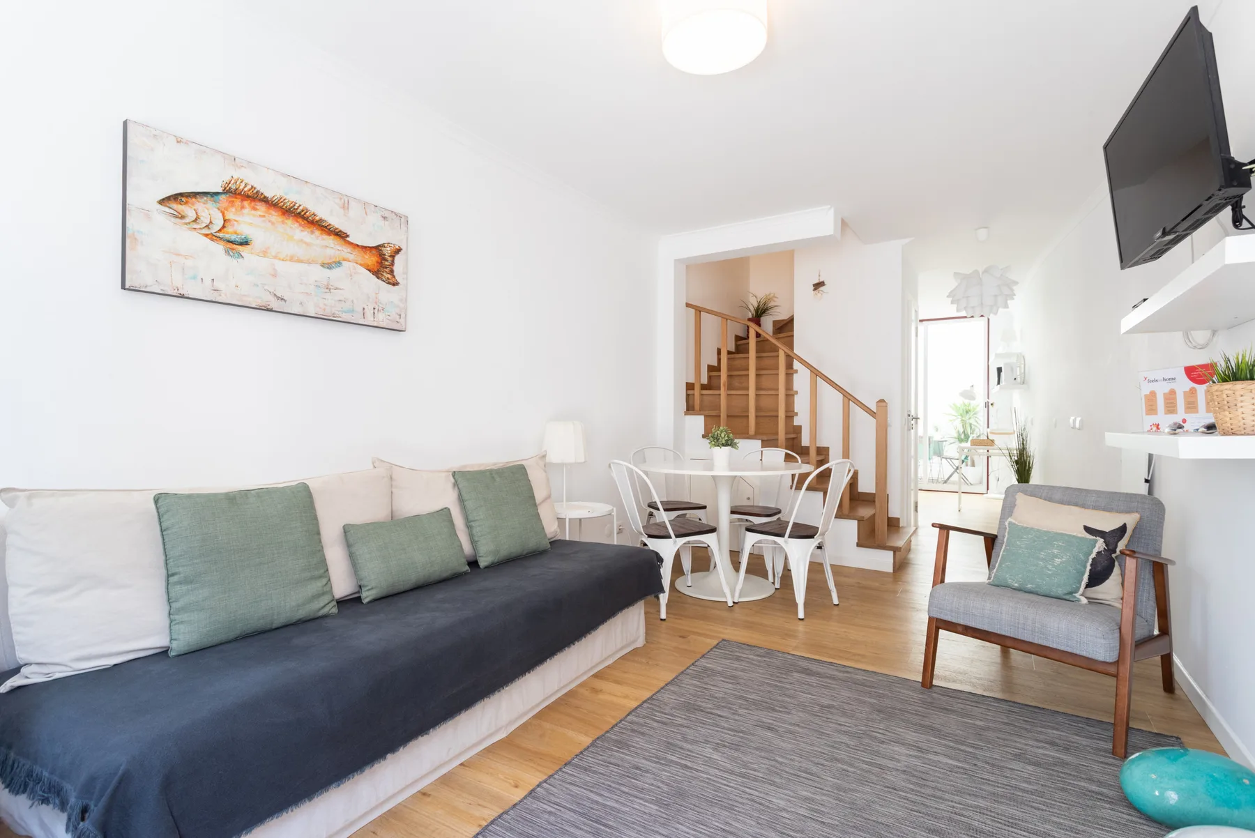Una sala de estar con asientos, una mesa de comedor y una escalera.