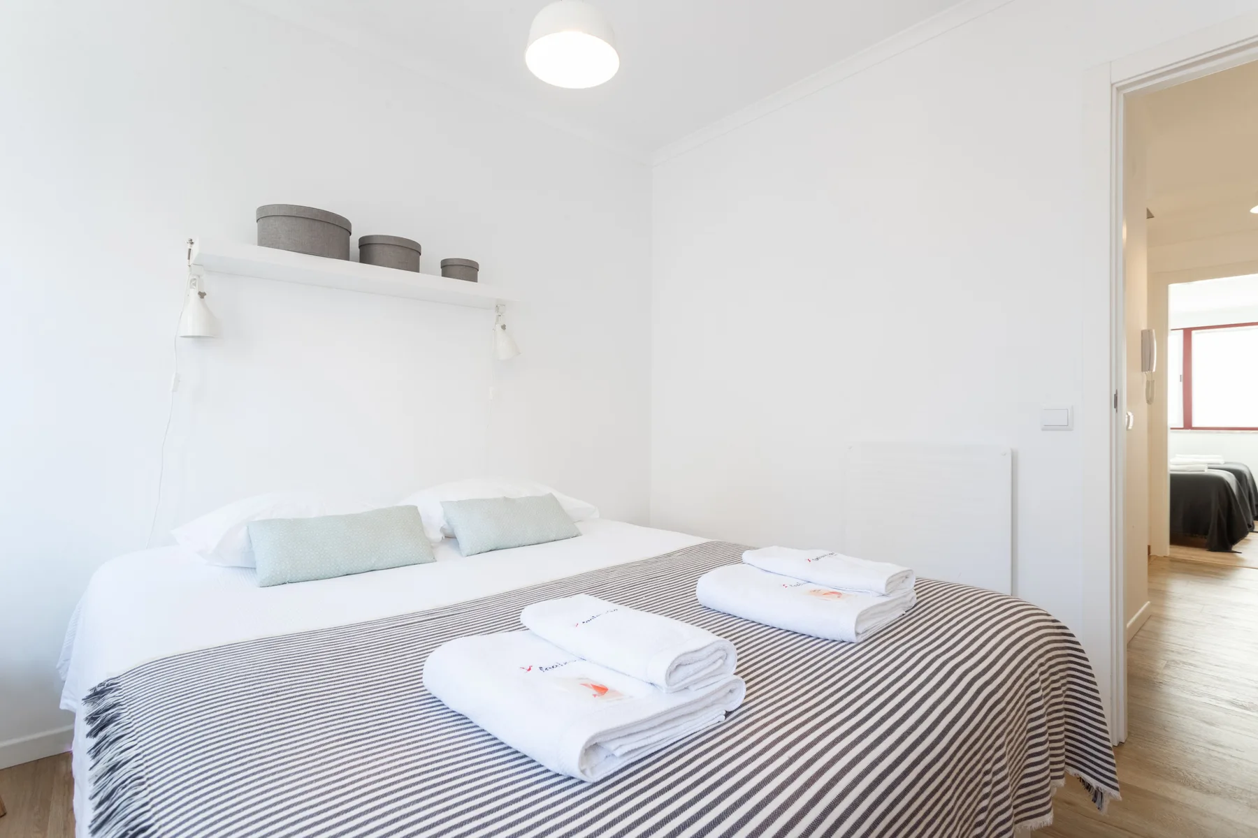 Un dormitorio luminoso con una cama bien hecha y toallas dobladas.