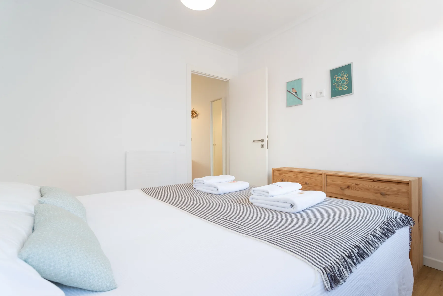 Un dormitorio con una cama, toallas dobladas y una cómoda de madera.