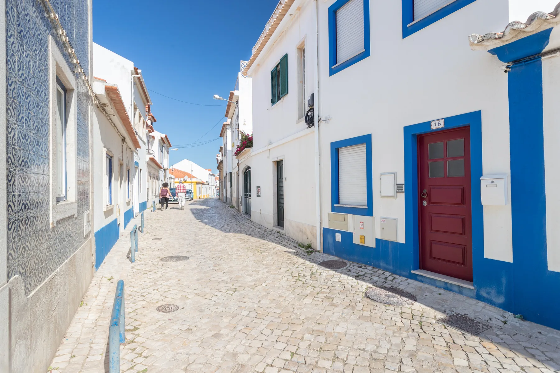 Una calle empedrada pasa entre edificios blancos con detalles azules.