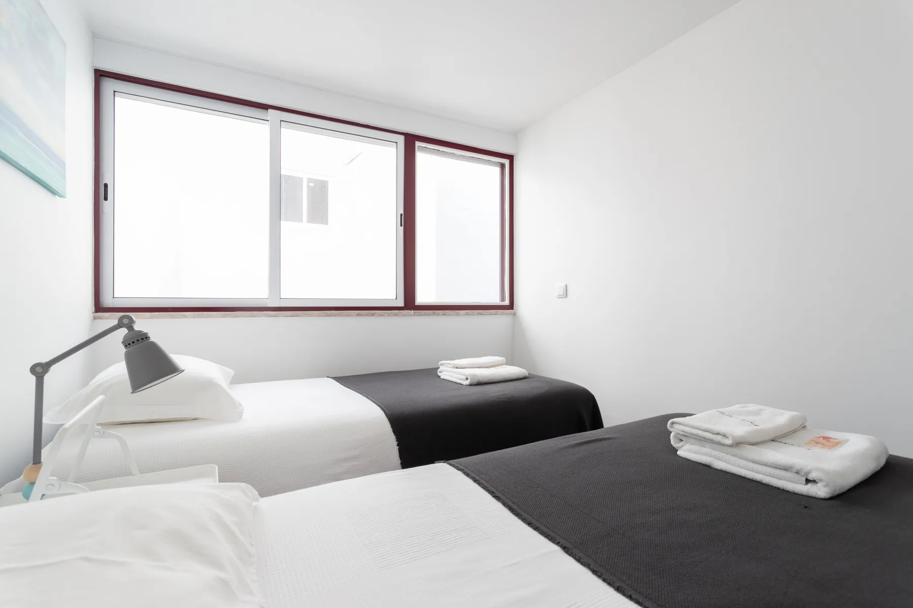 Un dormitorio luminoso con dos camas y una ventana amplia.