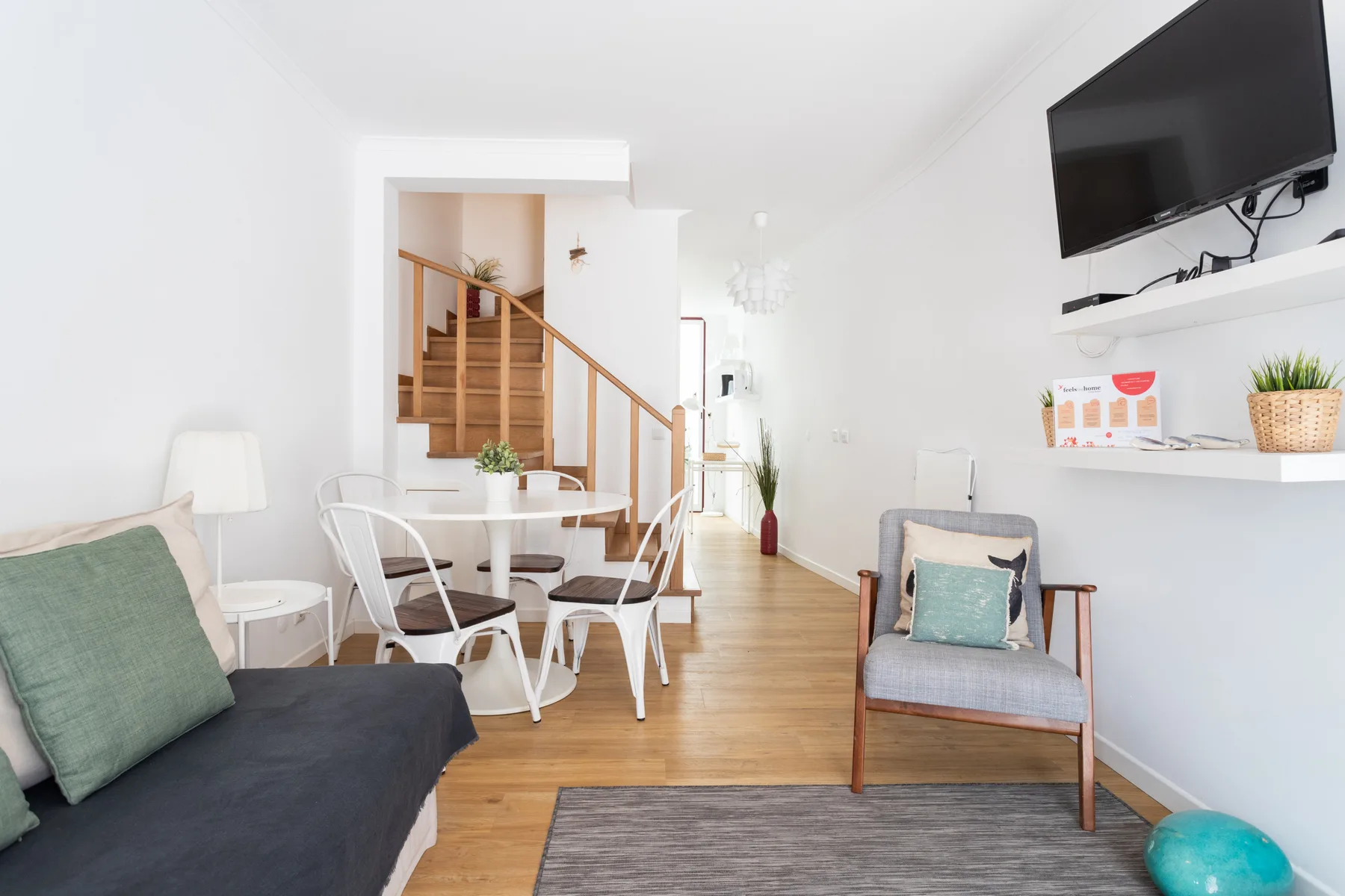 Una luminosa sala de estar y comedor con asientos, una mesa y una escalera.