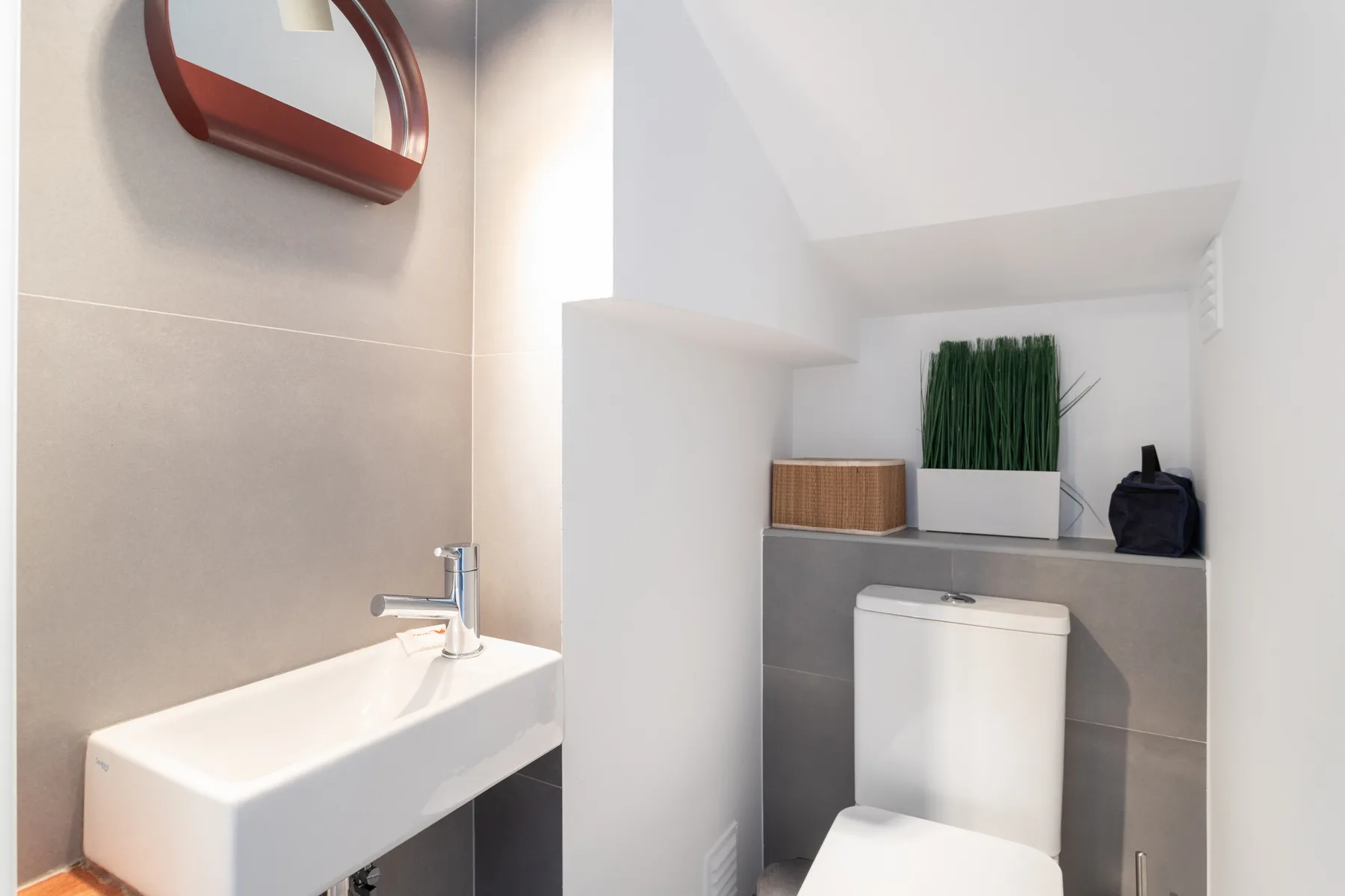 Un baño compacto con lavabo suspendido e inodoro.