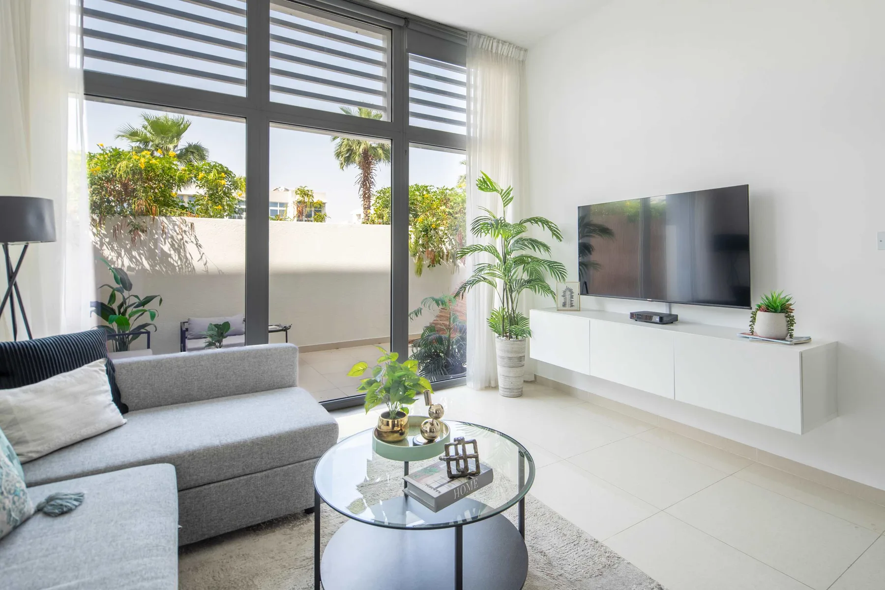 Una sala luminosa con asientos y un televisor junto a grandes ventanas.