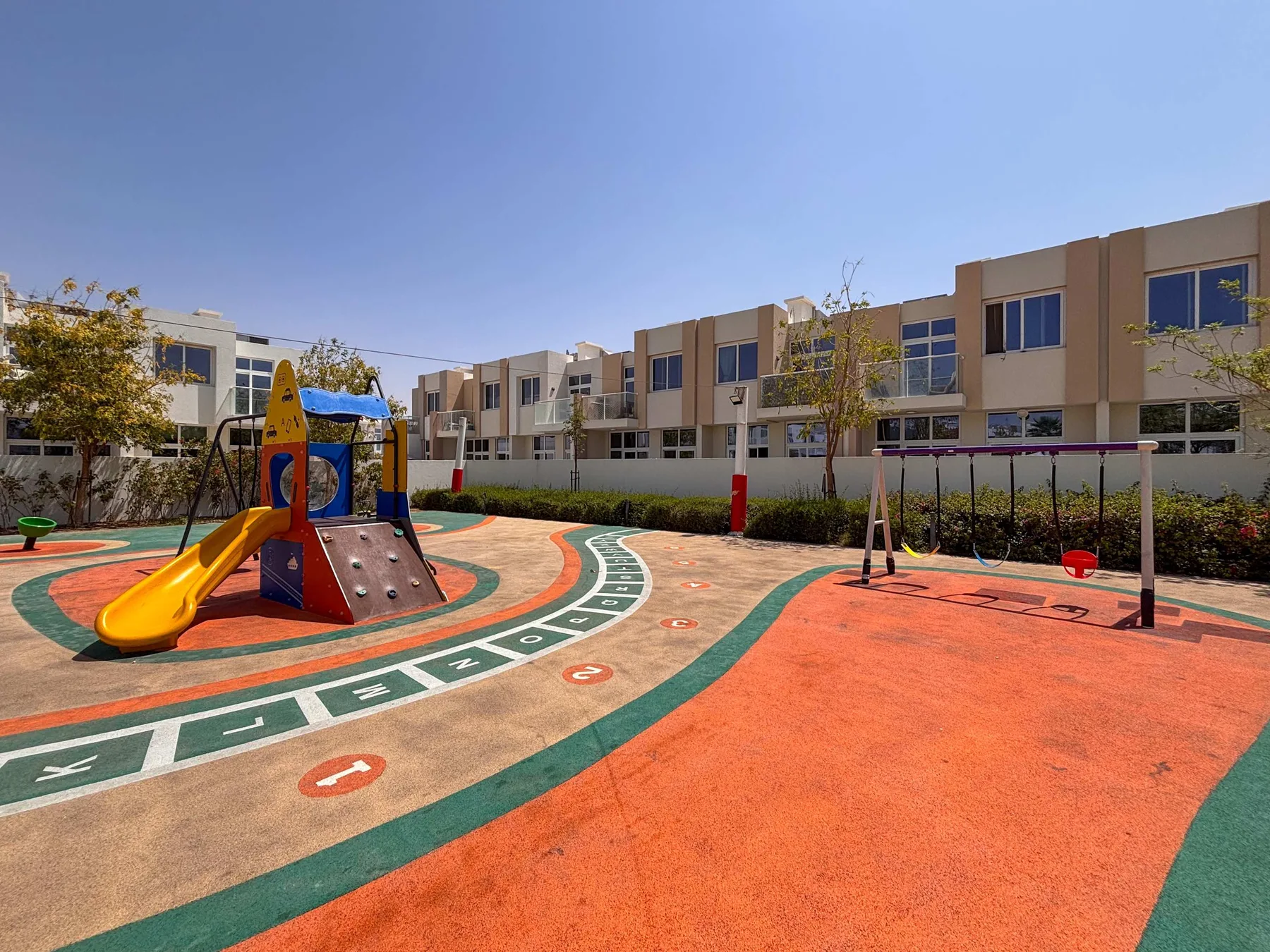 Un parque infantil al aire libre tiene una estructura para trepar y áreas de juego pintadas.