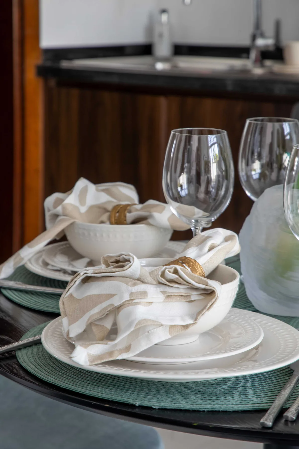 Una mesa está preparada con platos, servilletas dobladas y copas.