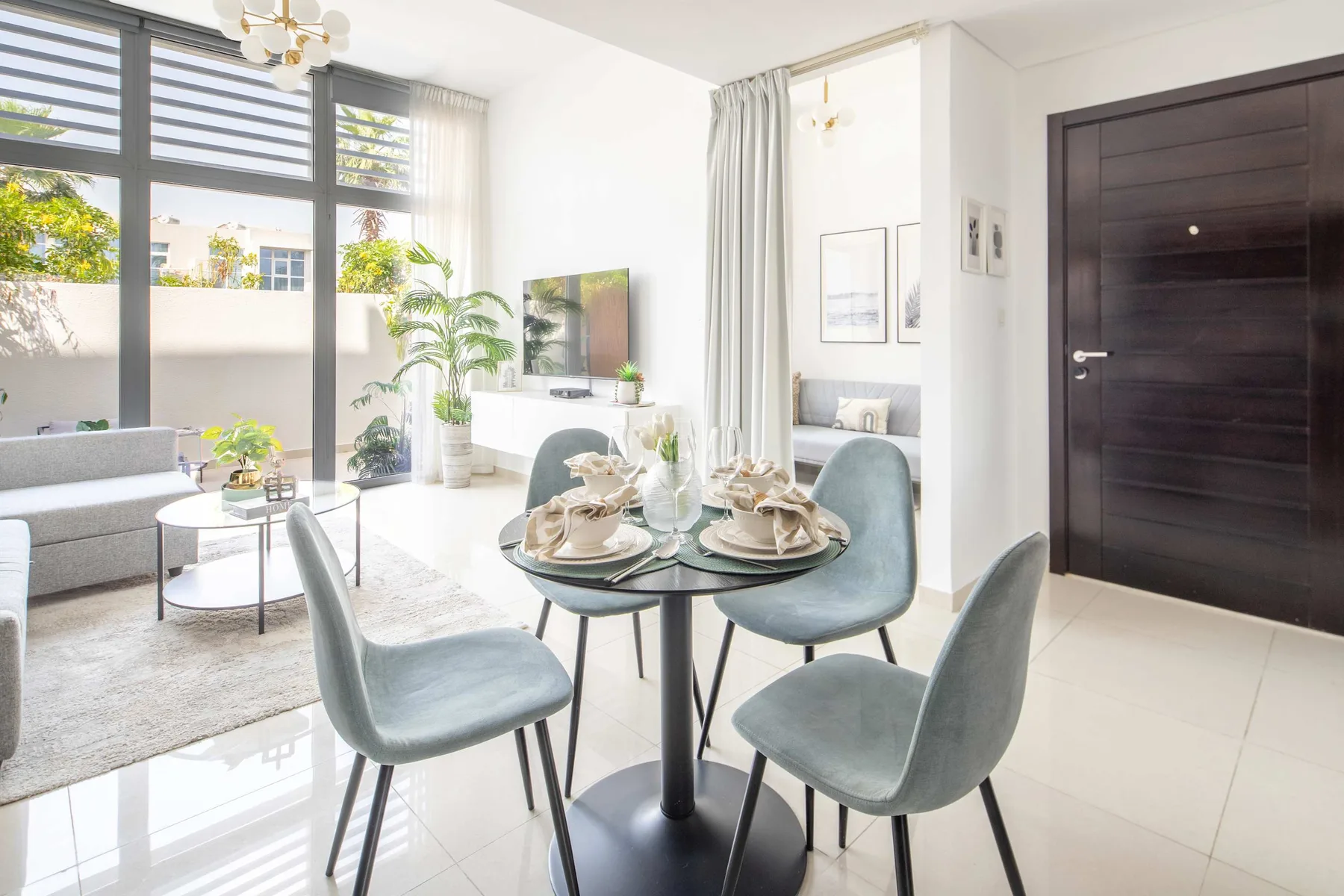 Un comedor luminoso con una mesa redonda y sillas junto a una sala de estar soleada.