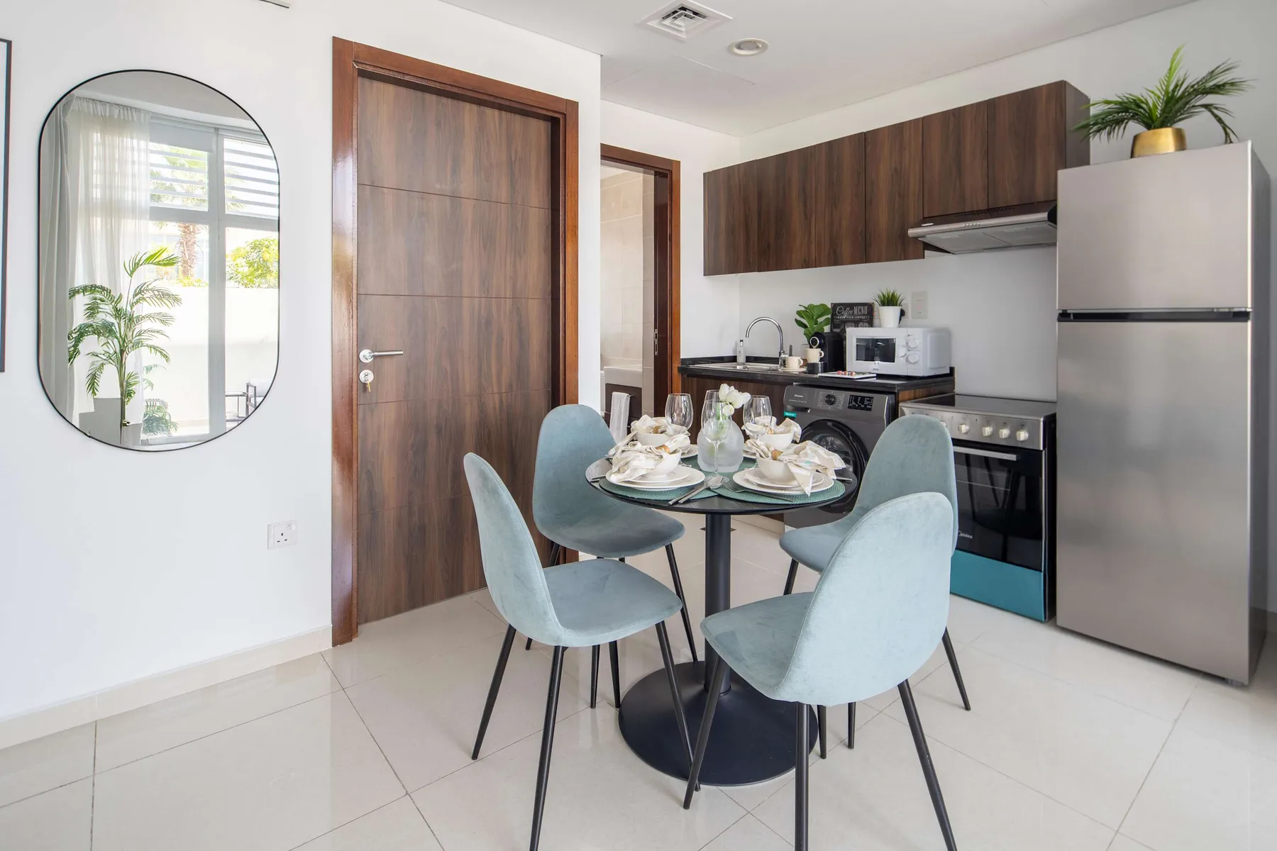 Comedor junto a una cocina compacta, con una mesa redonda y asientos tapizados.