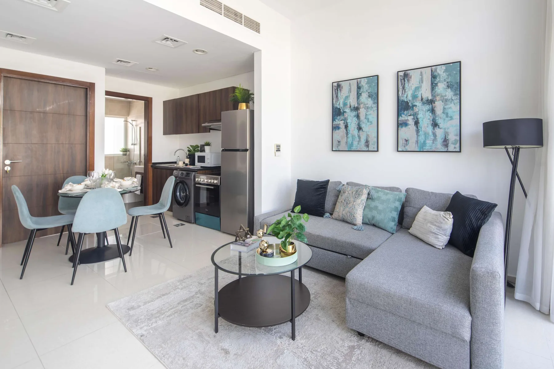 Una sala de estar y cocina abiertas con un sofá seccional gris y una mesa de comedor.