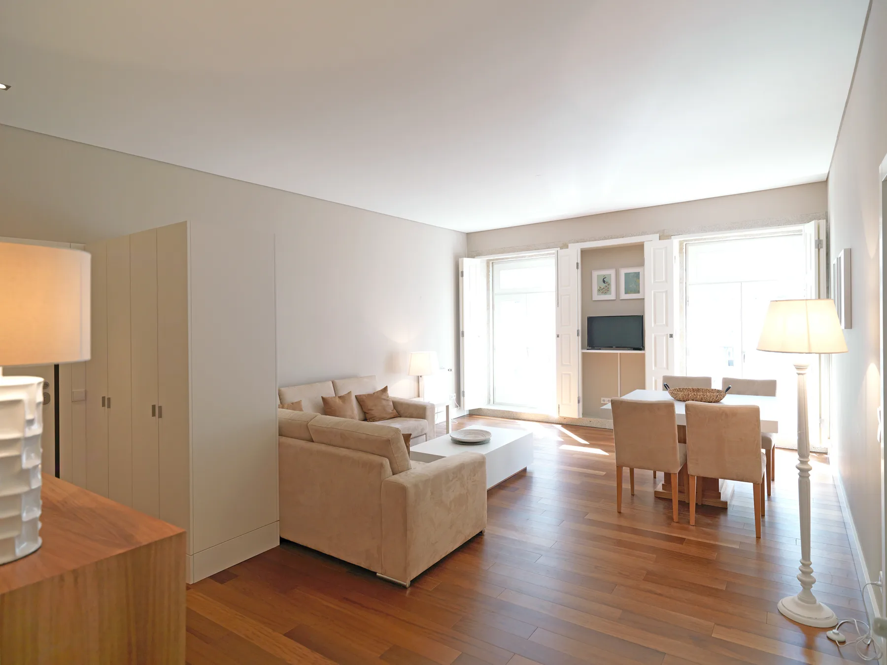 A bright living room with seating, a dining table, and large windows.