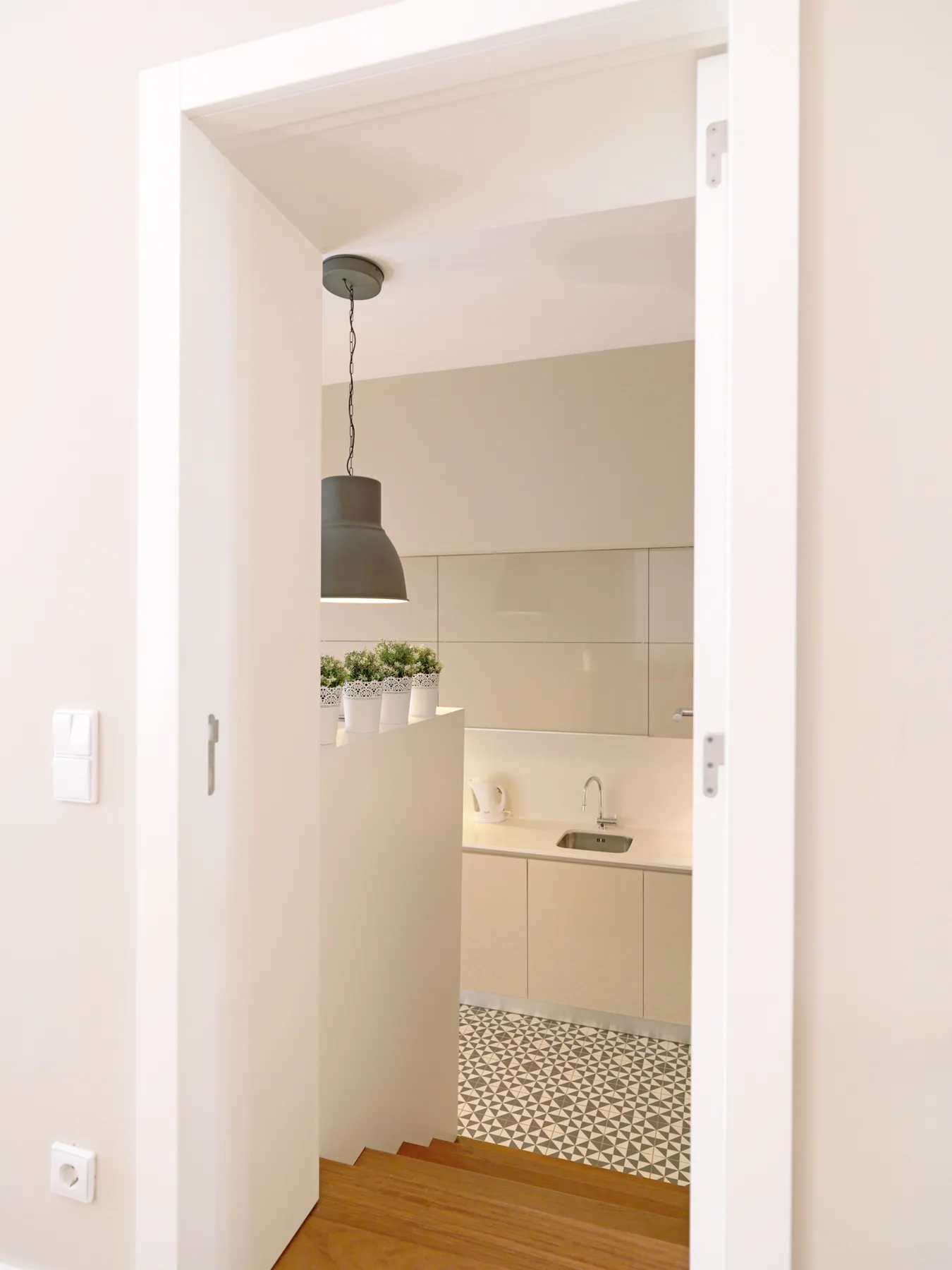 A bright kitchen with a countertop and patterned tile floor is visible through a doorway.