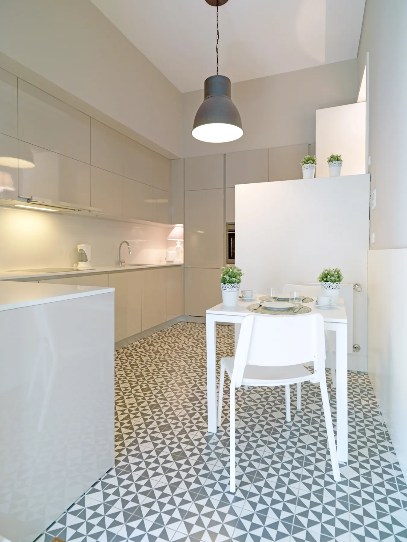 A bright kitchen and dining area with patterned floor tiles and a white table.
