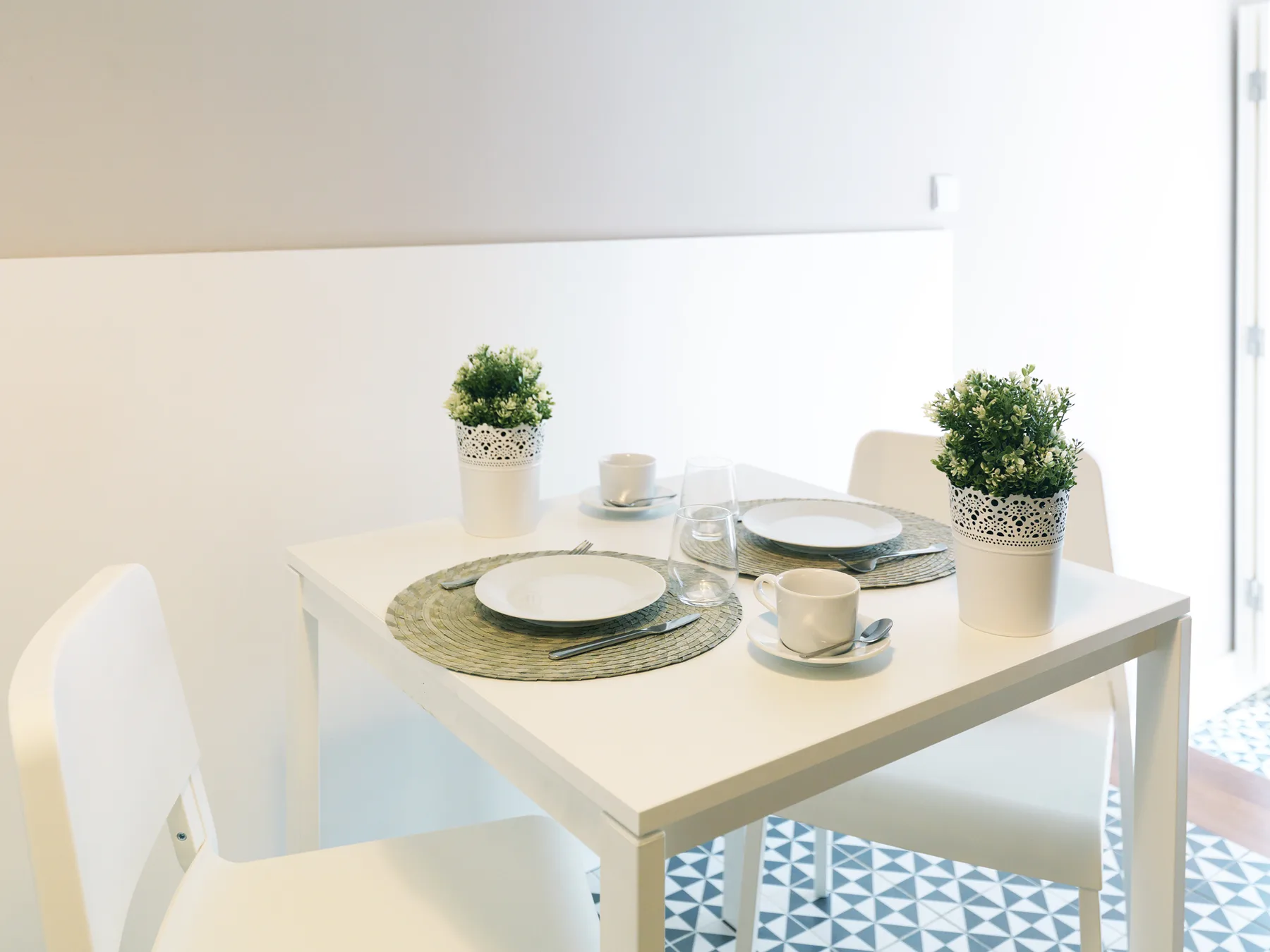 A bright dining area with a white table set with plates and cups.