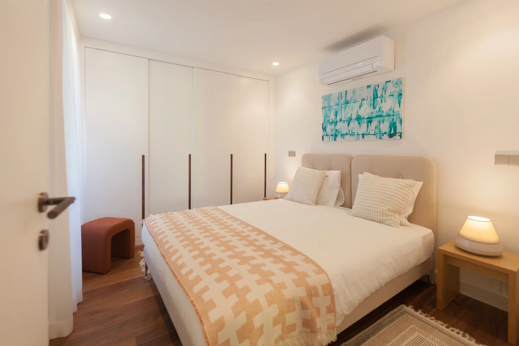 Dormitorio con cama doble, mesas de noche y aire acondicionado en la pared.