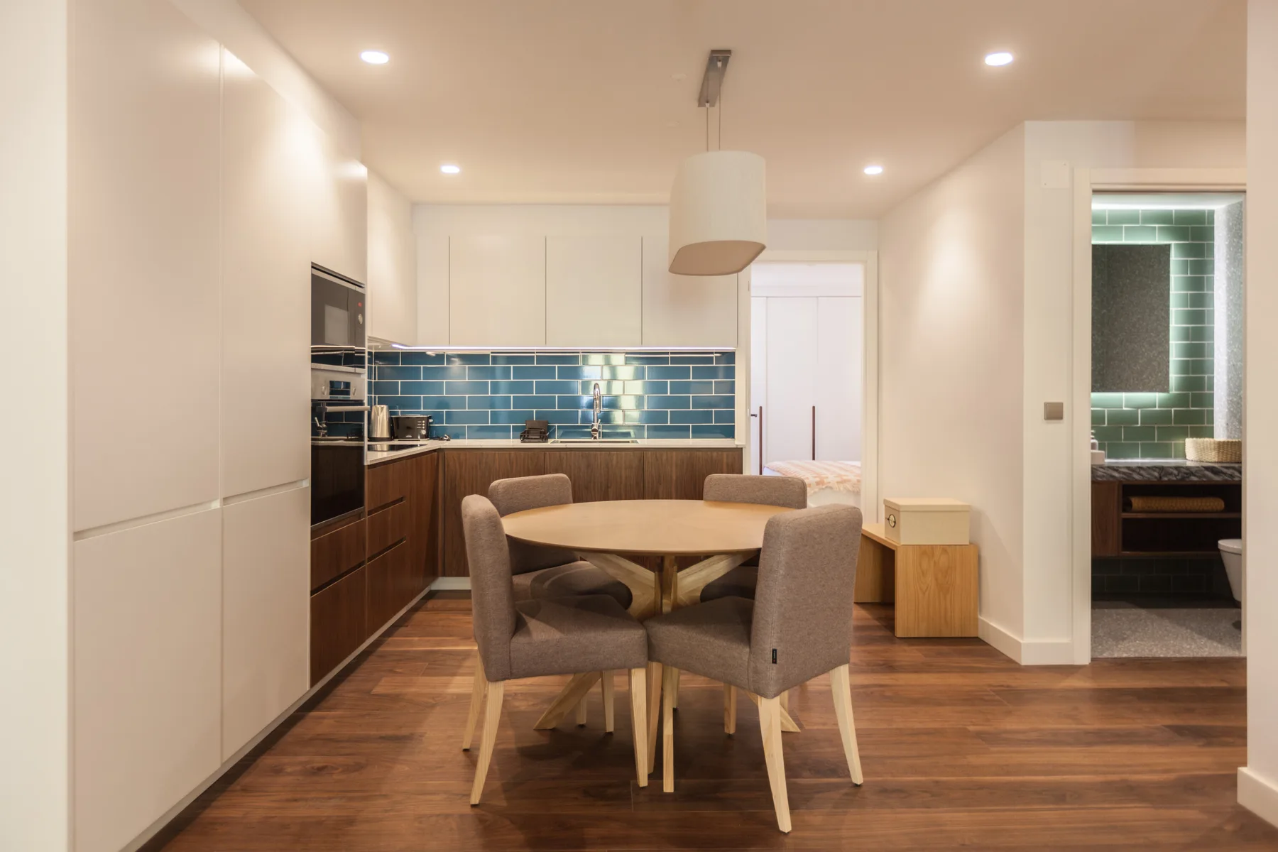 Comedor con una mesa redonda y asientos tapizados junto a la cocina.