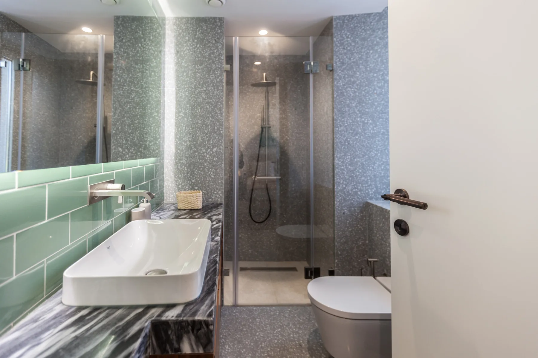 Un baño con lavabo, inodoro y ducha con mampara de vidrio.