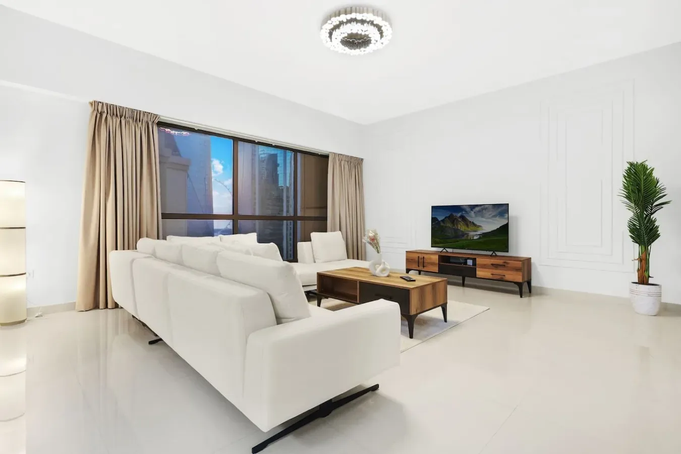 Bright living room with white seating, a coffee table, and a television.