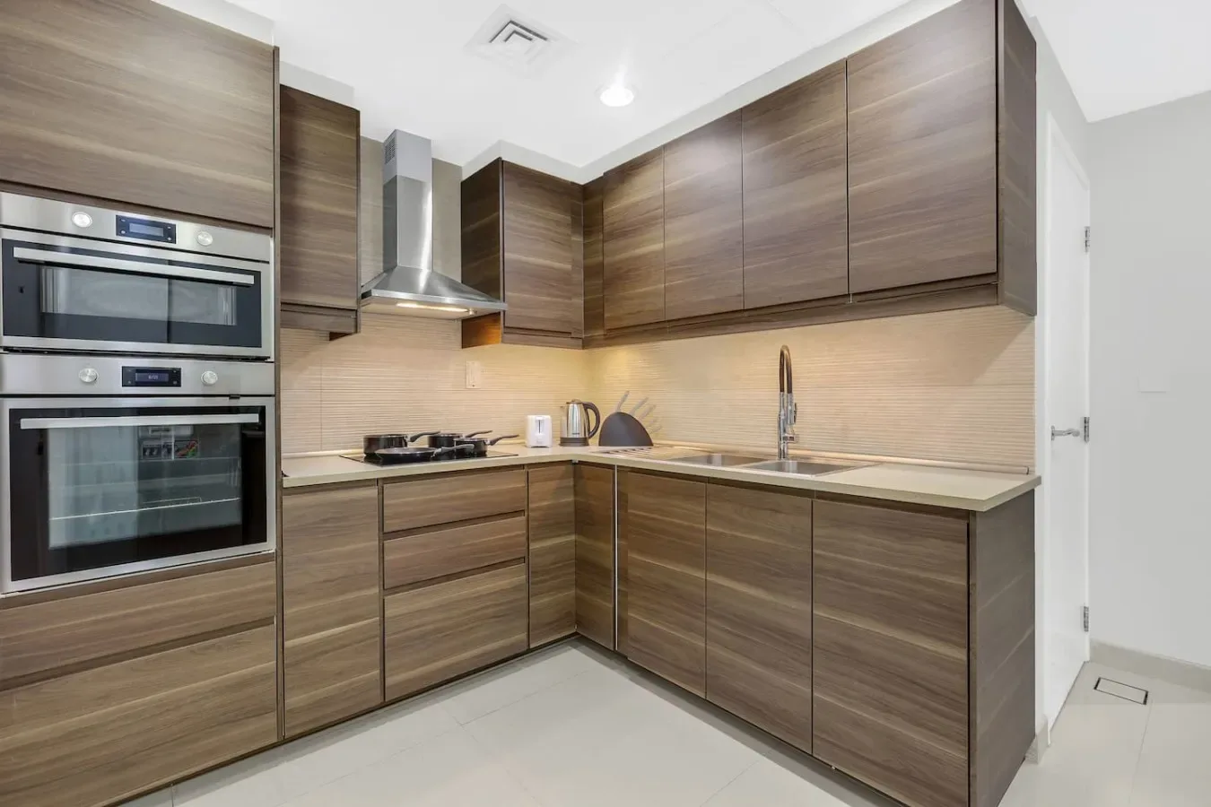 A modern kitchen with wood-finish cabinets, built-in ovens, and a sink.