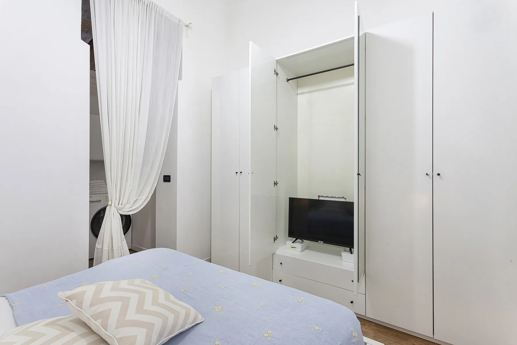 Un dormitorio con una cama y un televisor en un armario empotrado.
