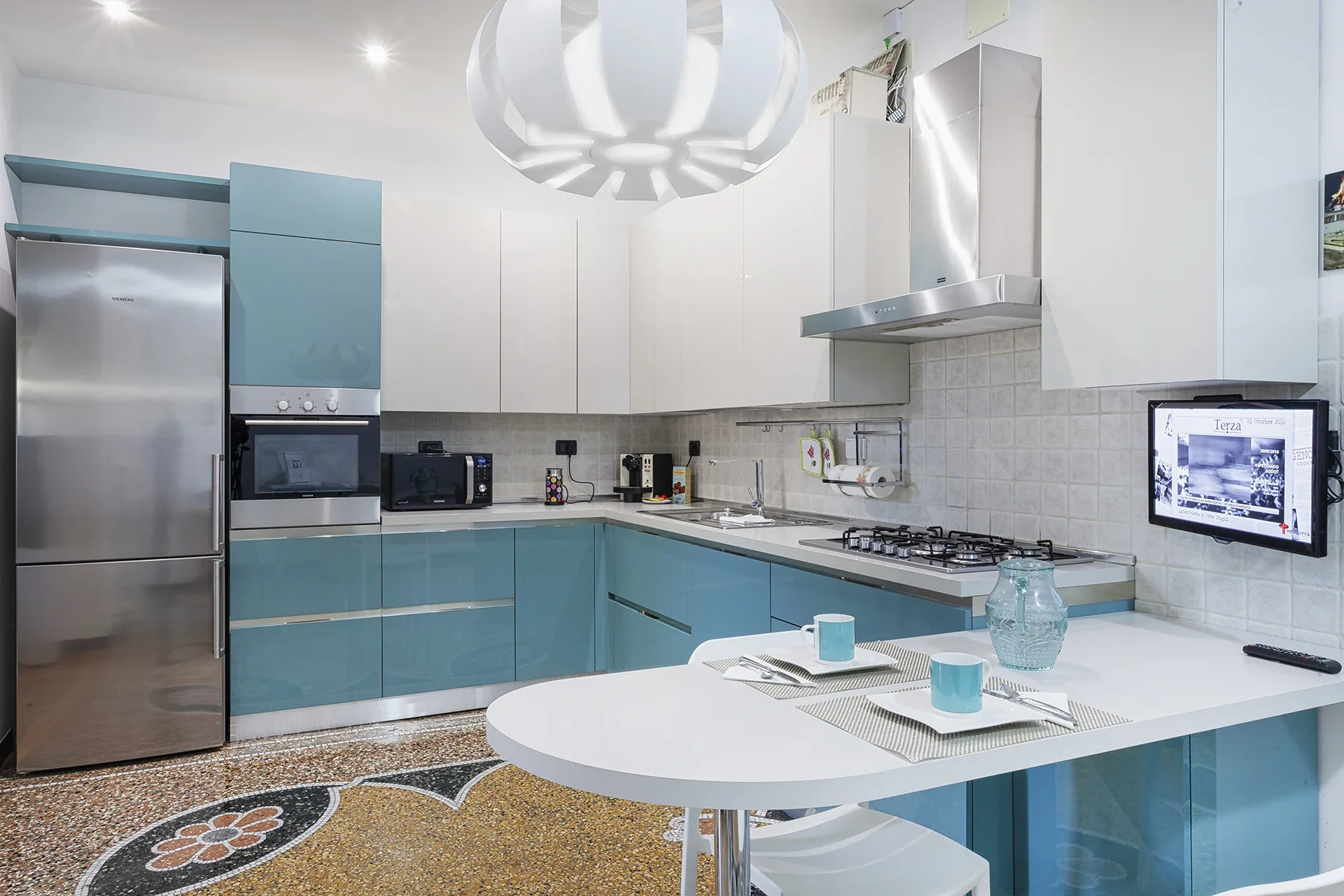 Una cocina moderna y luminosa con gabinetes azules, electrodomésticos de acero inoxidable y una mesa.