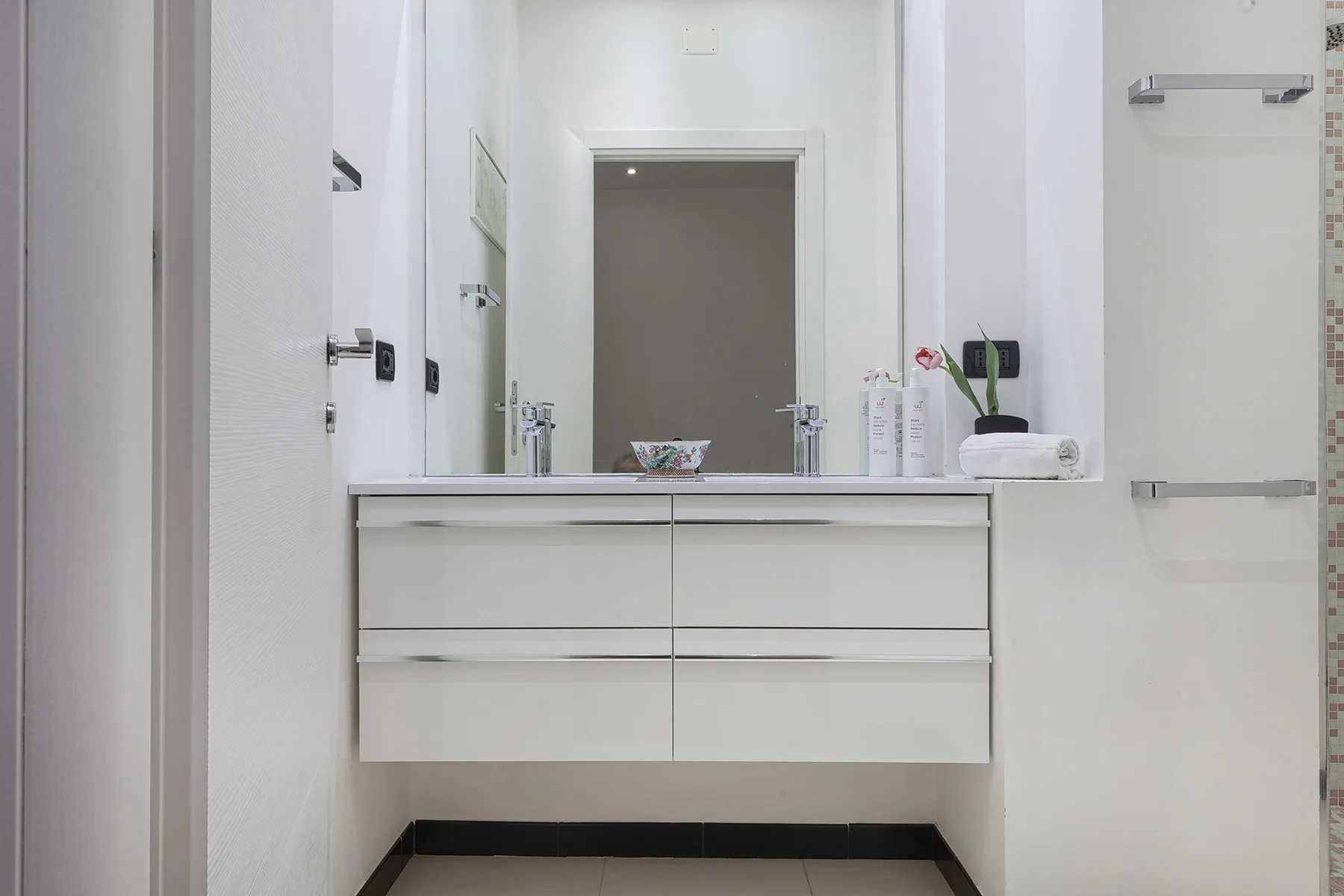 Un lavabo de baño con un espejo amplio y artículos de aseo sobre la encimera.