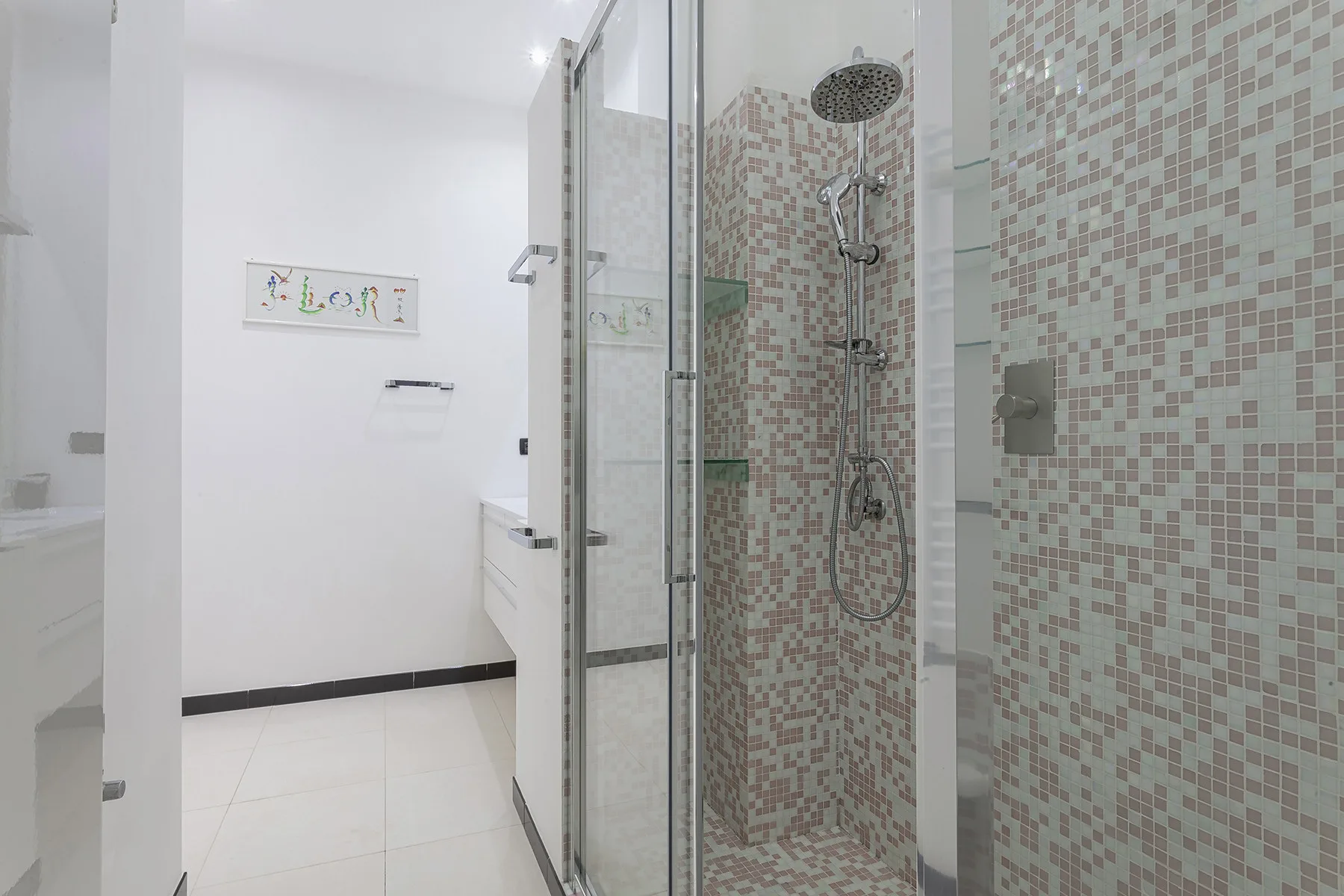 Un baño alicatado con una ducha de vidrio y un cabezal de ducha en la pared.