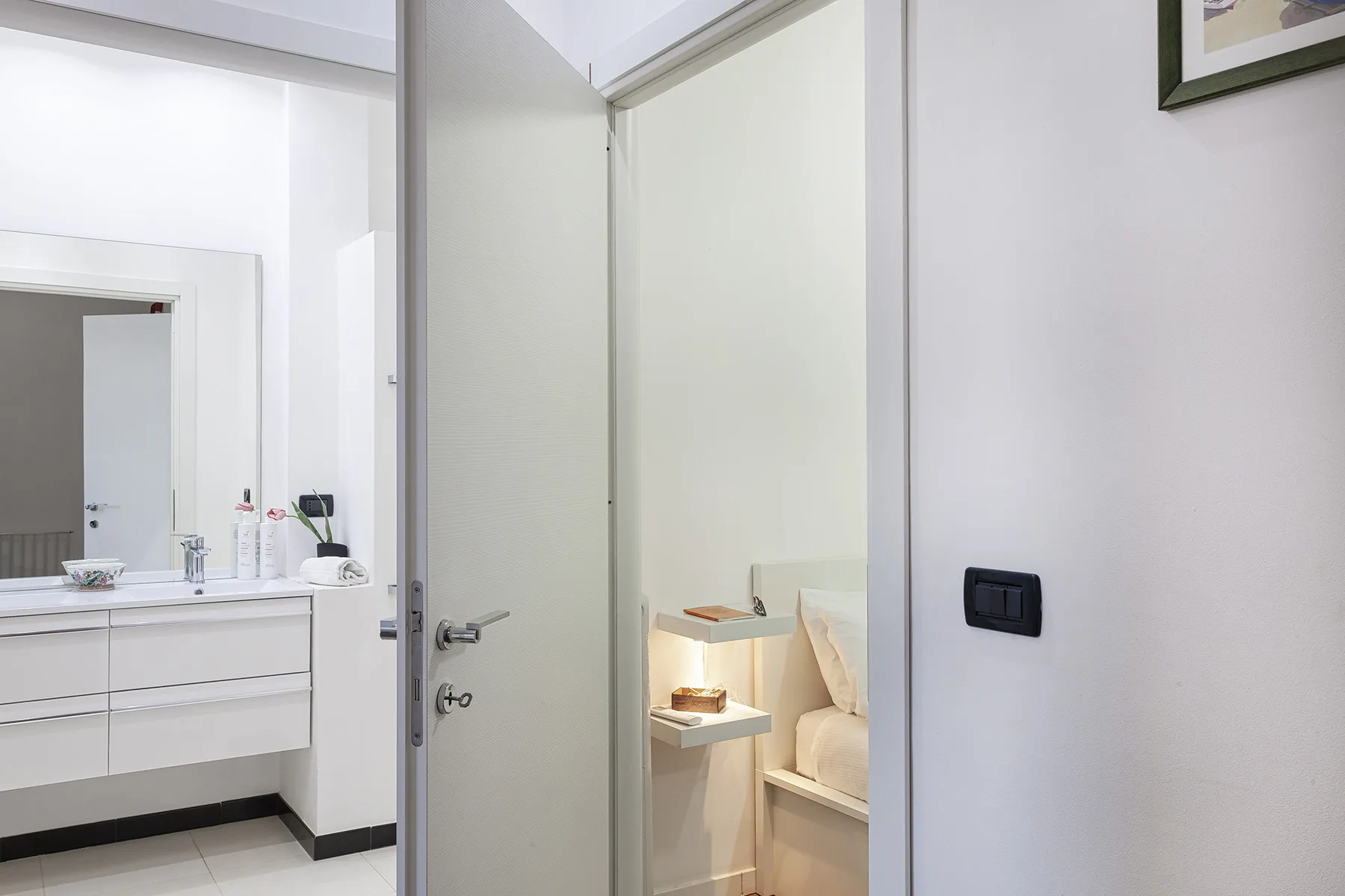 Se ve un dormitorio a través de una puerta abierta junto a un lavabo de baño.
