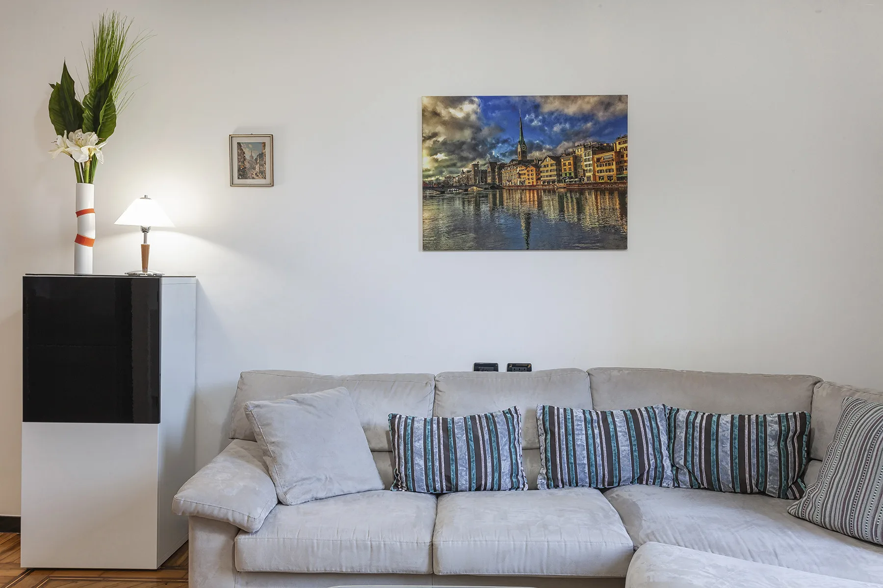 Una sala de estar con un sofá seccional claro y cuadros en la pared.