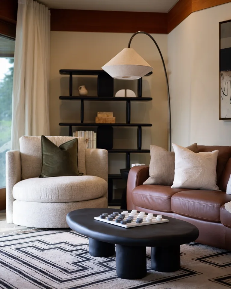 A living room with upholstered seating, a floor lamp, and a patterned rug.