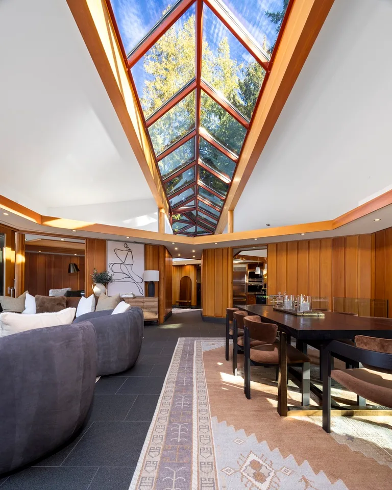 A furnished living and dining area sits beneath a long glass skylight.