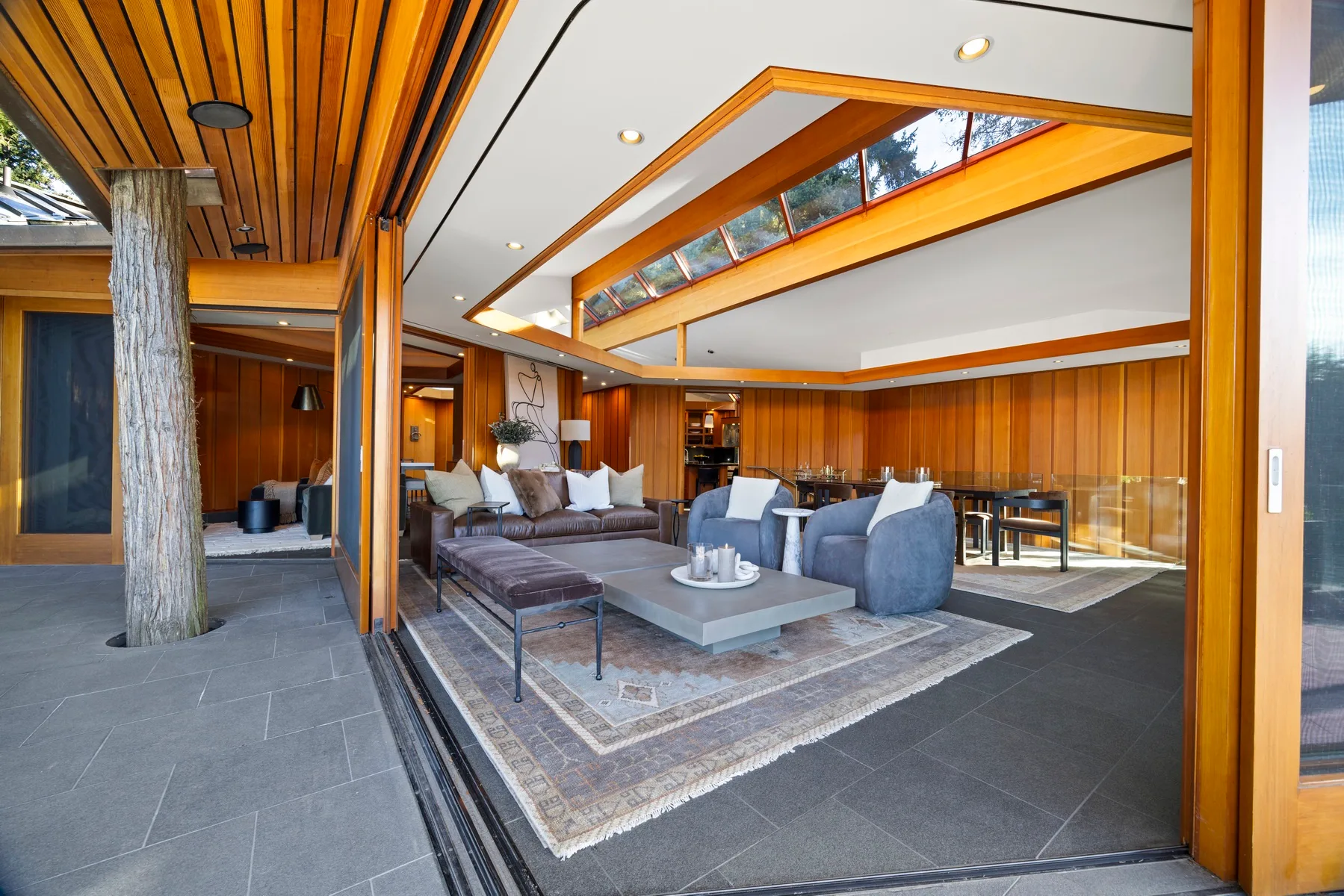 A spacious living room with seating around a low table and large windows.