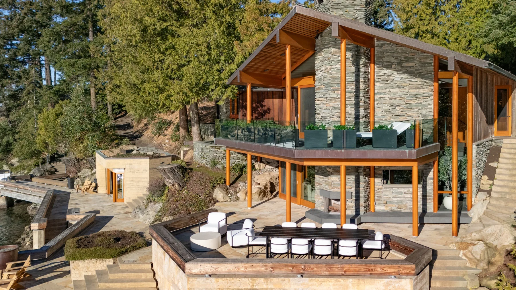A modern house with a stone exterior and a furnished outdoor terrace.