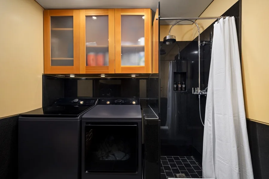A laundry area with dark appliances beside a shower.