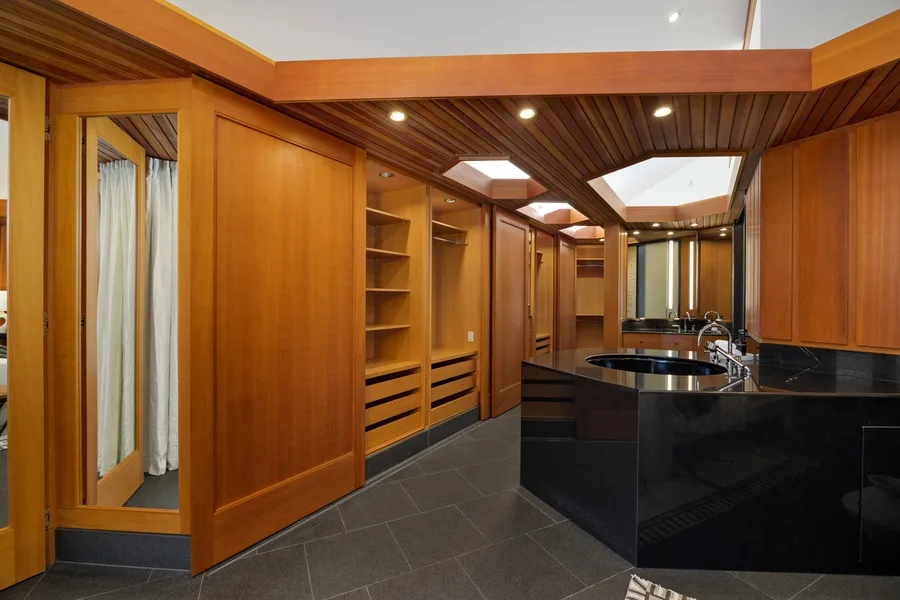 A wood-paneled bathroom with dark counters and sinks.