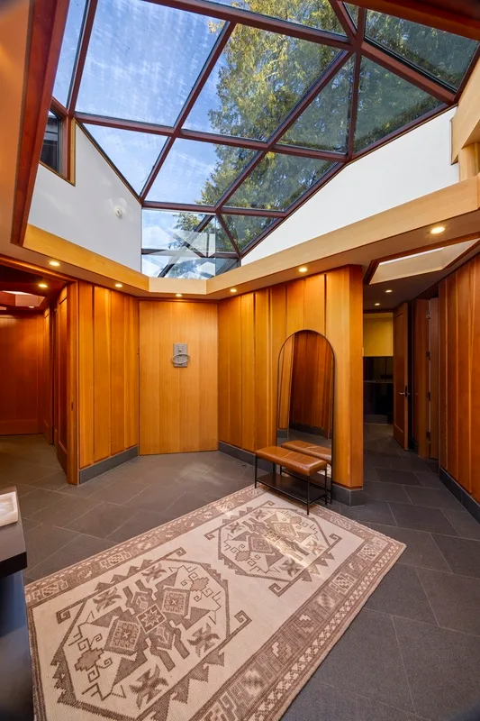 A wood-paneled interior with a glass ceiling and patterned rug.