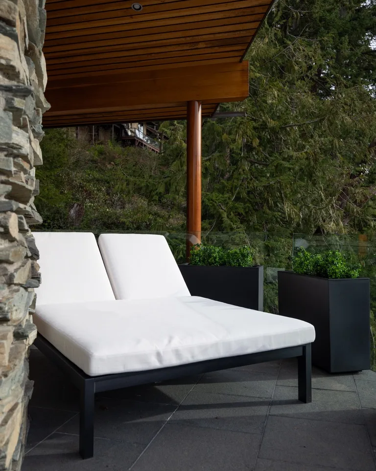 An outdoor patio seating area with a white cushioned lounge beneath a wooden awning.