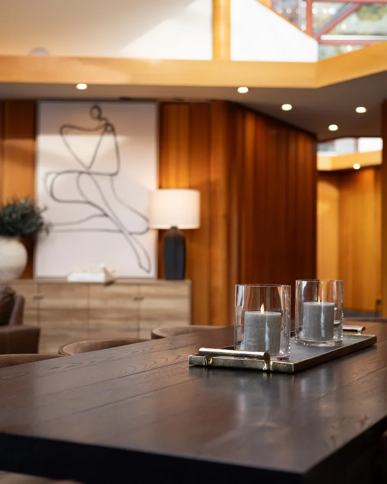 A warmly lit dining area with a dark table and abstract wall art.