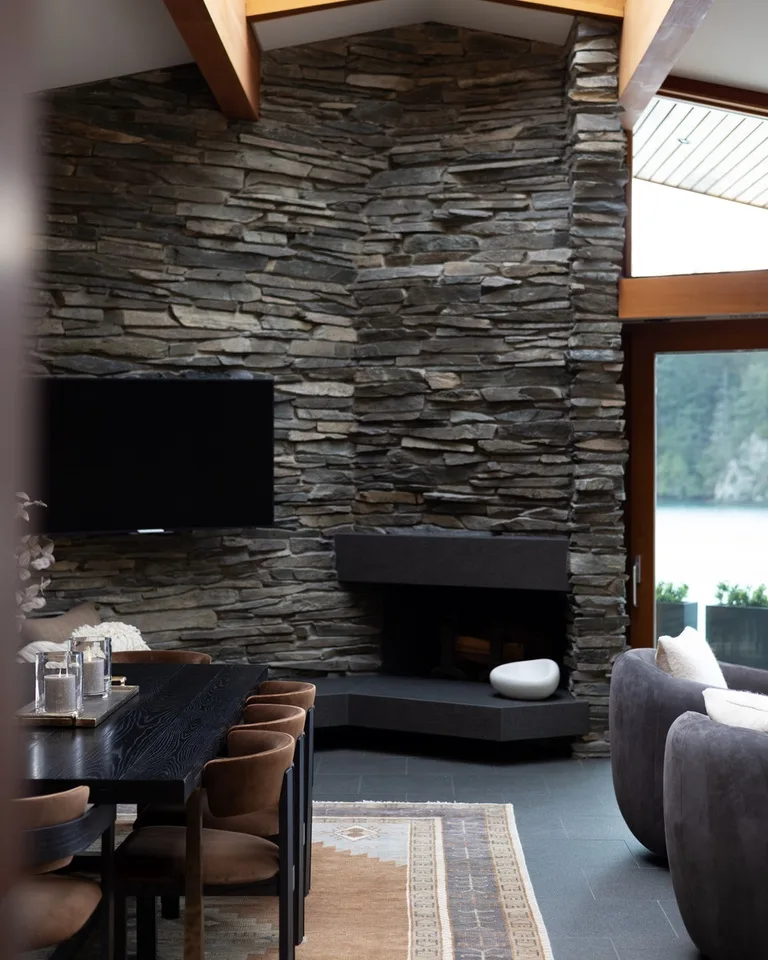 A modern living room with a tall stone wall and dark seating.