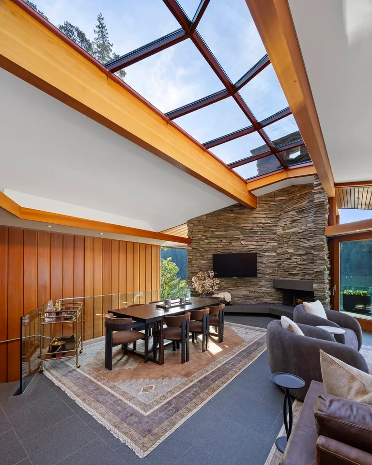 A bright living room with a dining table, seating, and a stone feature wall.