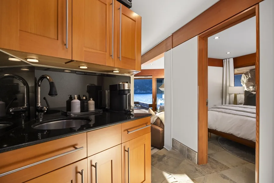 A compact kitchenette opens onto a bedroom with a neatly made bed.