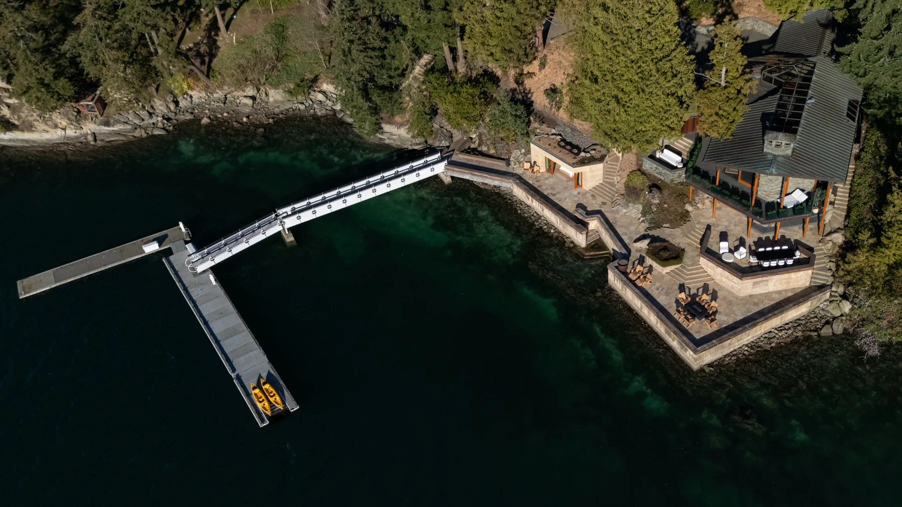 An aerial view of a lakeside deck and docks beside a wooded shoreline.