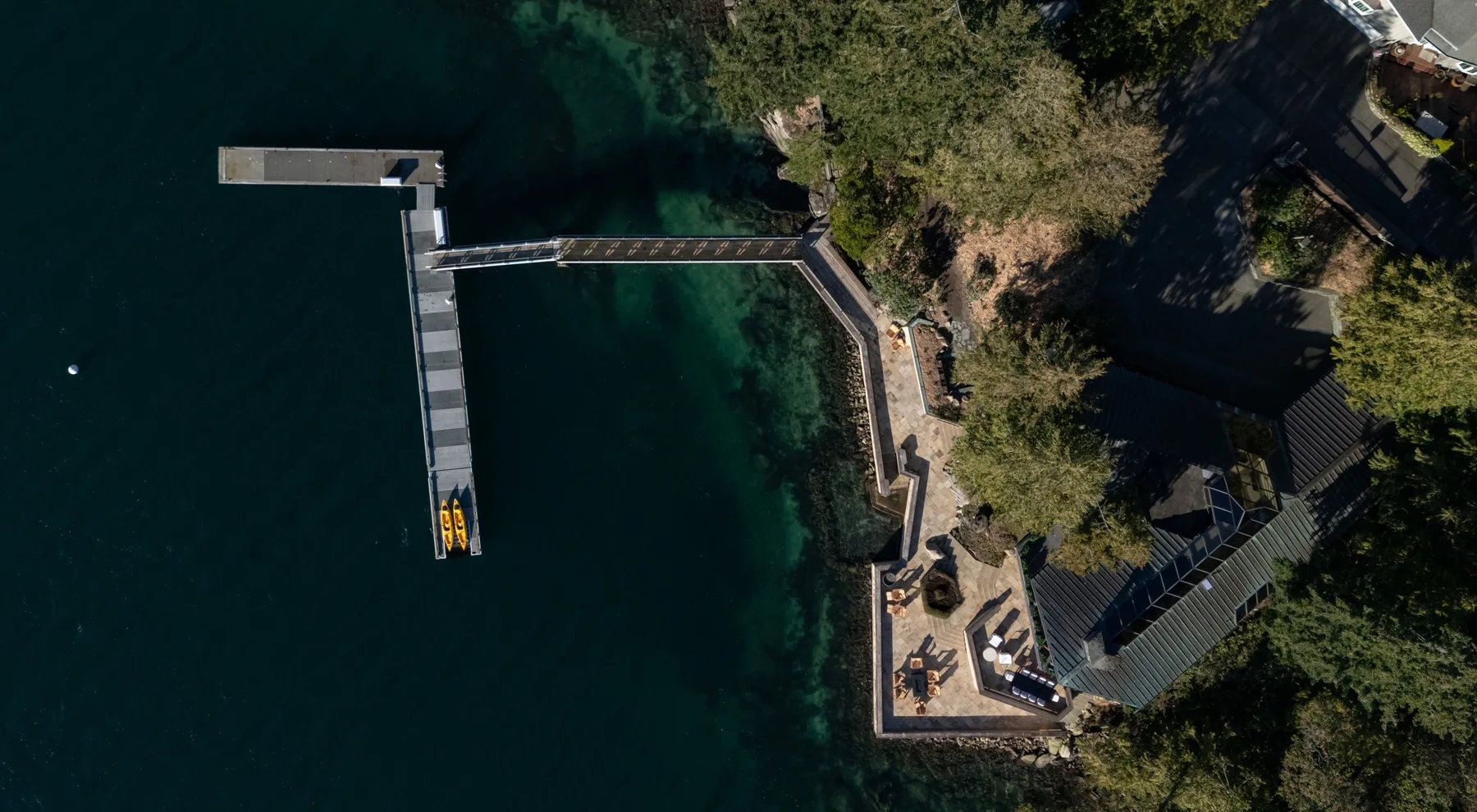 Aerial view of a waterfront property with a long dock extending into the water.