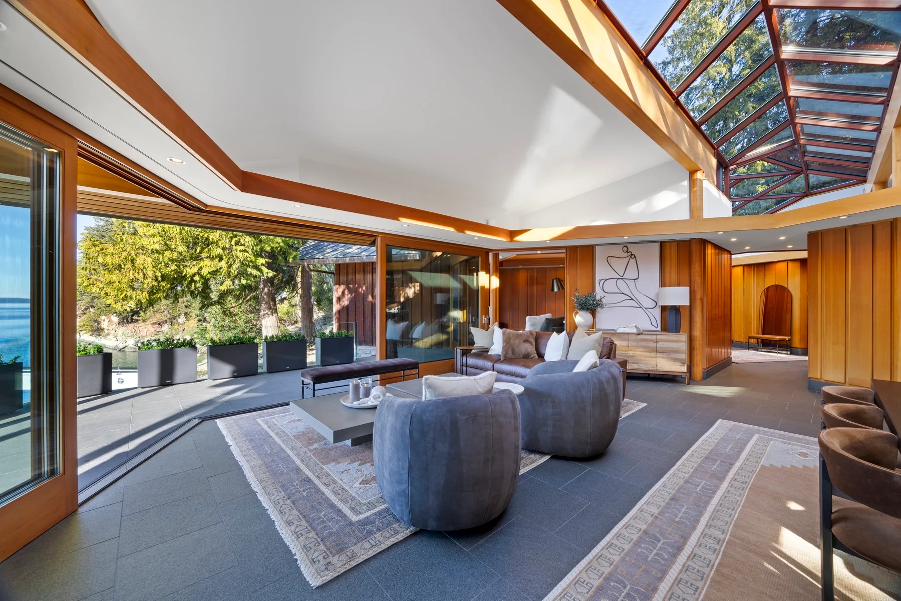 A spacious living room with seating beneath a high, skylit ceiling.
