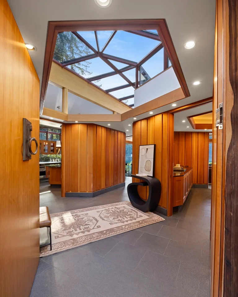 A wood-paneled interior opens beneath a large glass skylight.