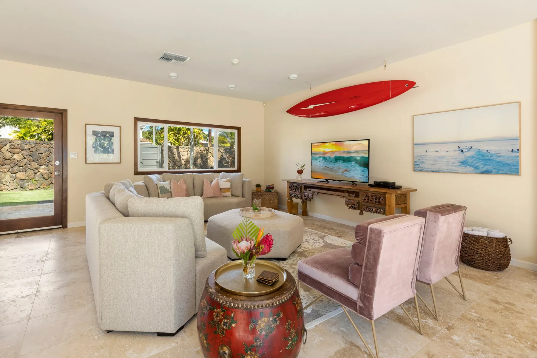 A bright living room with seating, a television, and colorful artwork.