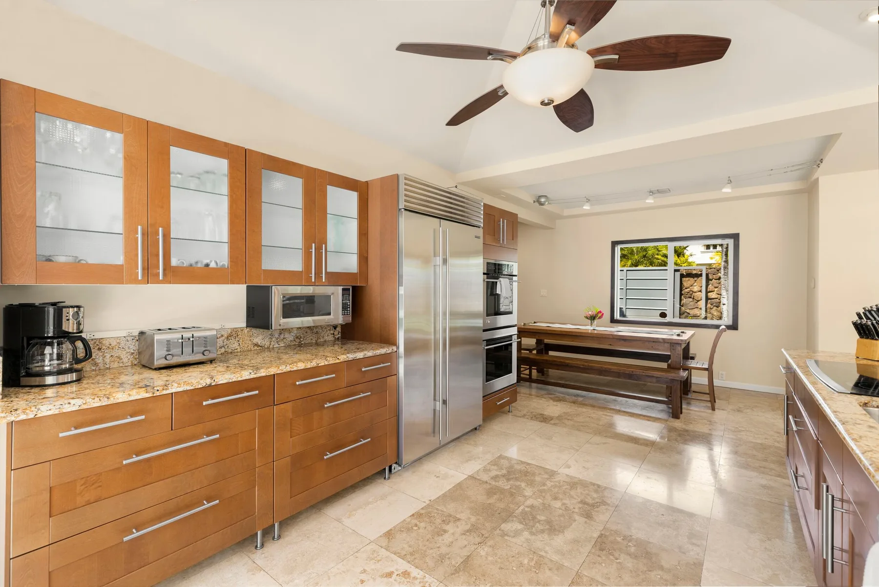 A spacious kitchen with wood cabinets, stainless steel appliances, and a dining table.