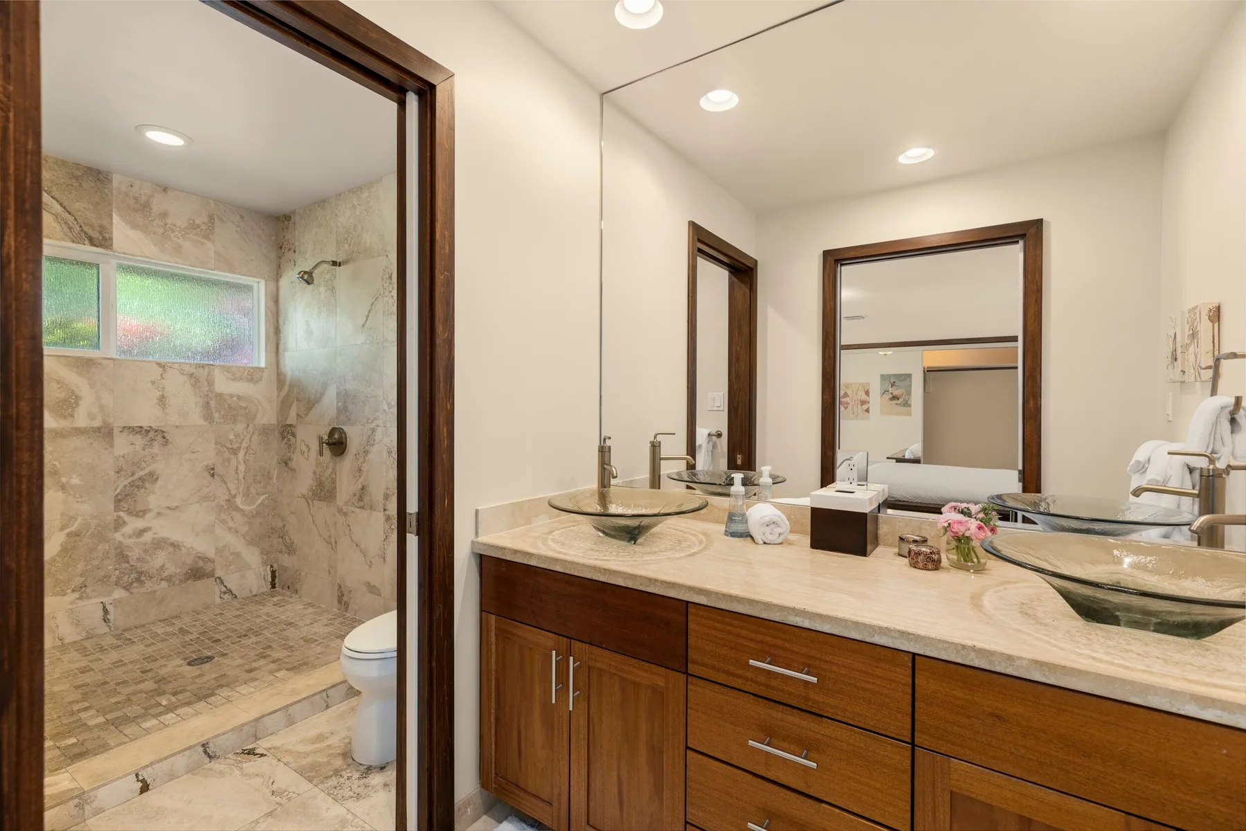A bathroom with a long vanity and a walk-in shower.