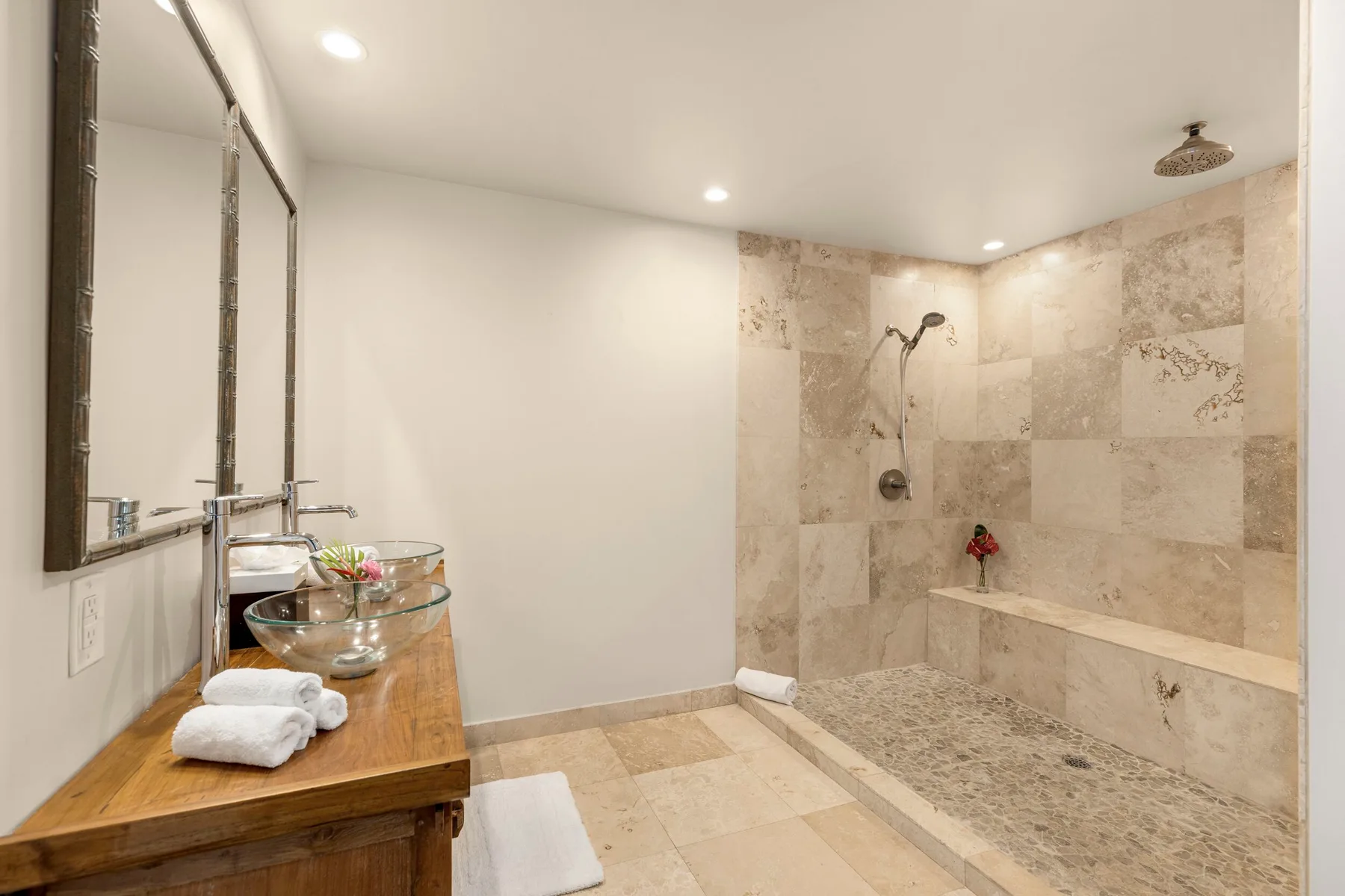 A bathroom with a stone-tiled shower and a wooden vanity.