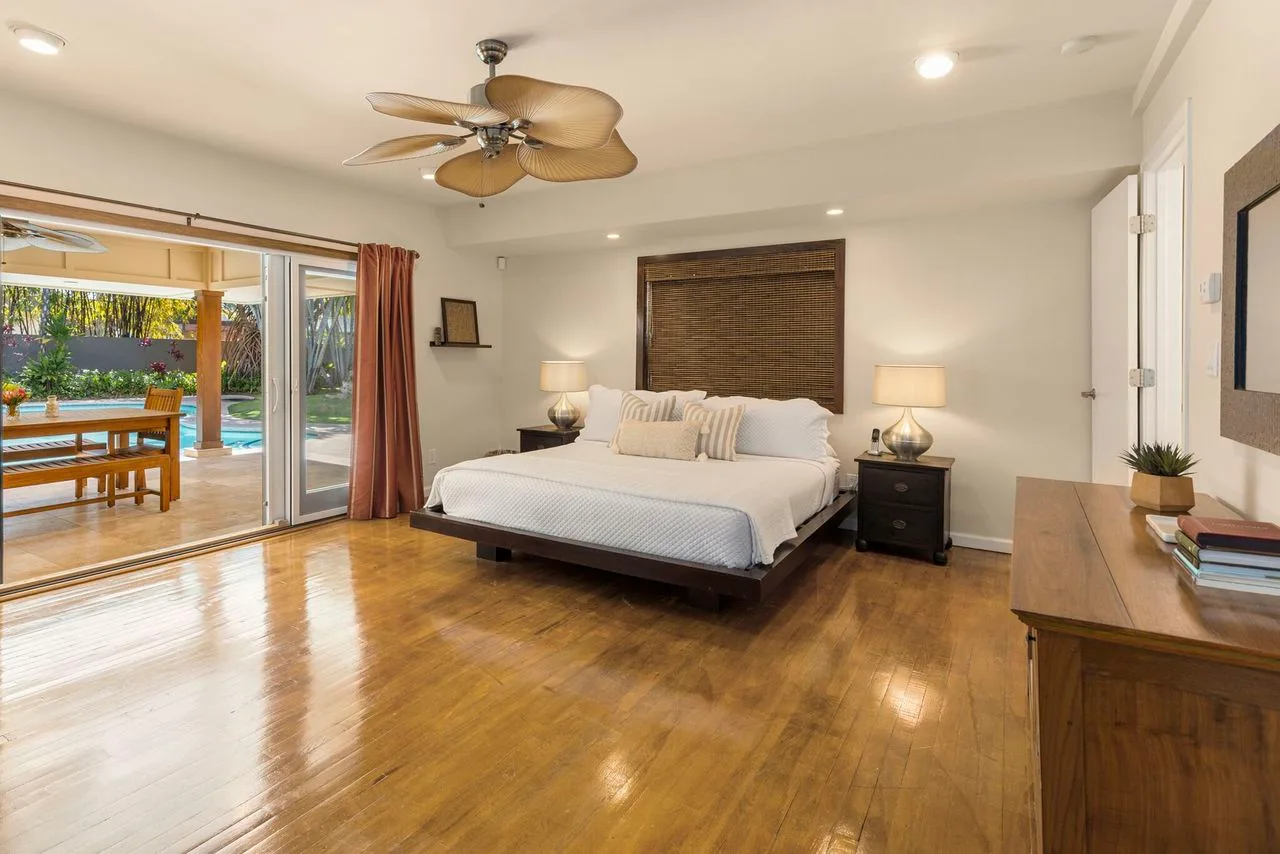 A bedroom with a bed, bedside tables, and sliding glass doors opening to a patio.
